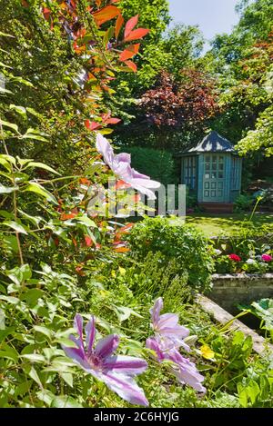 House Back garden from kitchen window, with bespoke summerhouse and beautiful flower displays, enclosed by trees, secluded, design, Central Scotland, Stock Photo