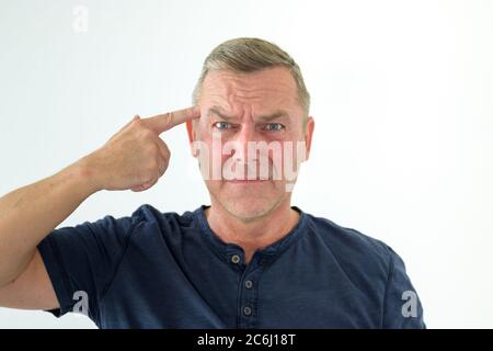 Angry man making a threatening gun gesture with his hand pointing at his own forehead Stock Photo