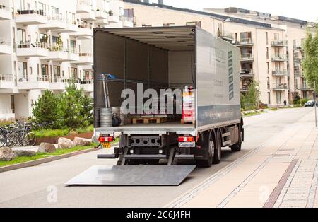 Delivery truck being unloaded with tailgate loader open in front of a residential building with goods in the cargo hold. Copenhagen, Denmark - Stock Photo