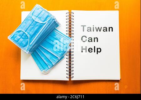 epidemic healthcare concept ,Taiwan Can Help text written on a notebook  ,Alcohol spray and face mask on wooden background Stock Photo