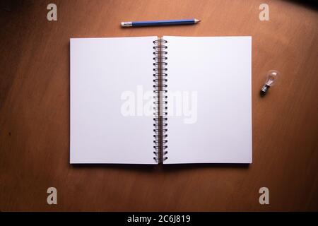 Top view, Light bulb, open blank notebook and pencil on a light wooden table, New idea, Innovation and Solution concepts. copy space Stock Photo
