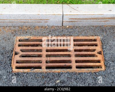 rusty grate of drain system on new city asphalt road Stock Photo