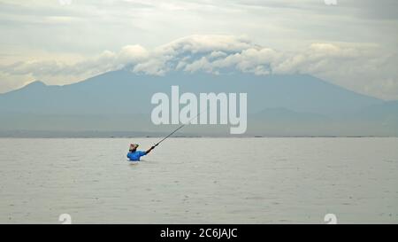 Indonesian fisherman catches a fish during a tropical rain on the island of Bali. Stock Photo