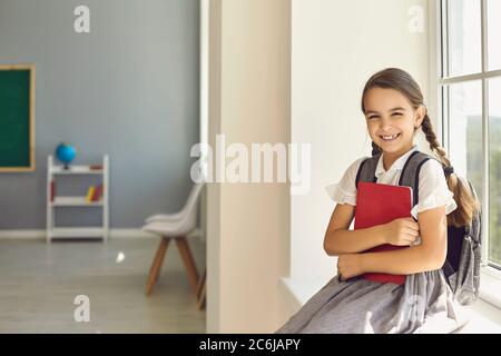 Back to school. Schoolgirl with a backpack and books in hands l in the classroom Stock Photo