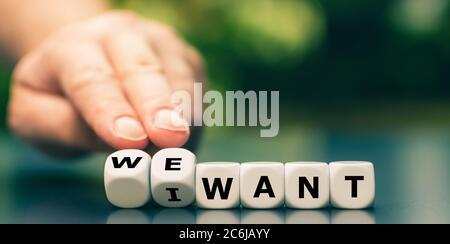 Hand turns dice and changes the expression "I want" to "we want". Stock Photo