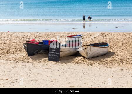 Fishing boats advertising fresh fish today for sale on beach at Durley Chine, Bournemouth, Dorset UK in July Stock Photo