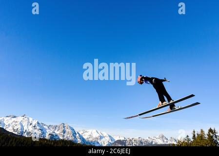 Ski jumpers jump from the large hill at the Nordic World Championships, Seefeld, Austria, 2019. Karwendel Alps in distance. Stock Photo