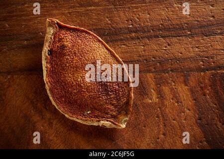 Single piece of dried orange rind on old wooden board. Stock Photo