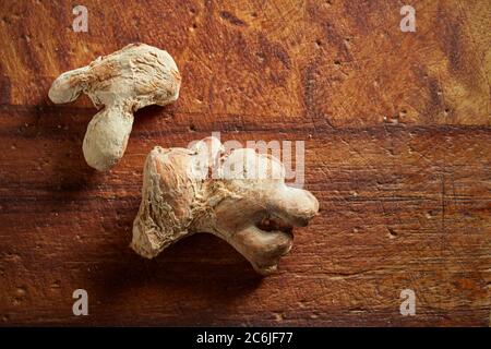 Pieces of dried ginger root on old wooden board. Stock Photo