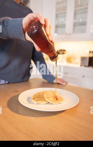 Mid section of woman pouring honey on pancakes Stock Photo