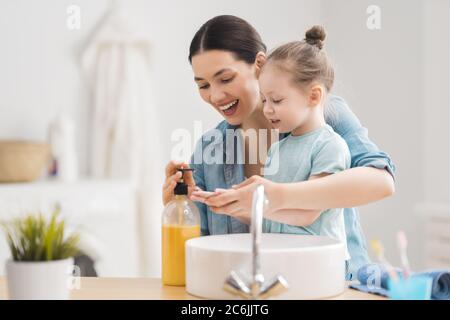 A cute little girl and her mother are washing their hands. Protection against infections and viruses. Stock Photo