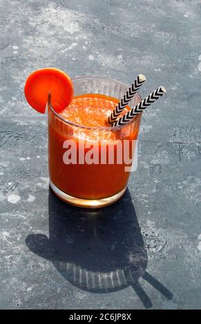 Detox carrot juice with black and white straws on a grey background. Fresh organic vegetarian drink and slices of carrots. Healthy food and diet conce Stock Photo