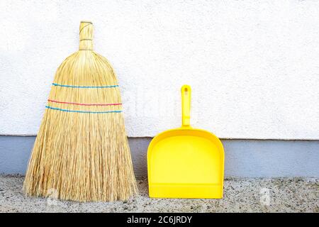 Yellow dustpan and broom outside. Cleaning equipment and tools Stock Photo