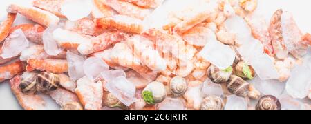 assortment of frozen seafood on ice cubes, shrimps, Babylonia areolata shellfish snails, langoustines, rich in iodine, antioxidants and vitamin, close Stock Photo