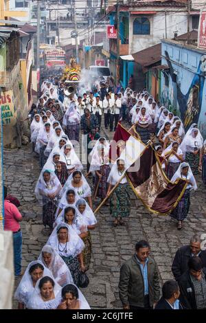 Guatemala, Solola Department, San Pedro la Laguna, Catholic procession of the Virgin of Carmen. Women in traditional Mayan dress with white mantillas over their heads.  Women carry the image of the Virgin in the procession. Stock Photo