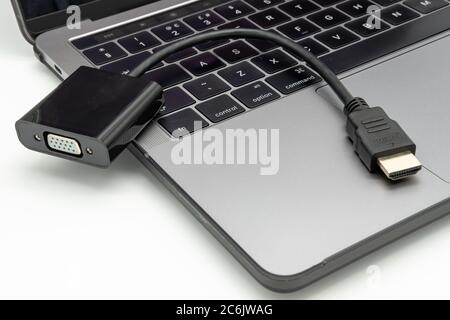 Detailed image of a HDMI video adapter seen laying on the keyboard of an opened, well-known brand of Notebook computer. Stock Photo
