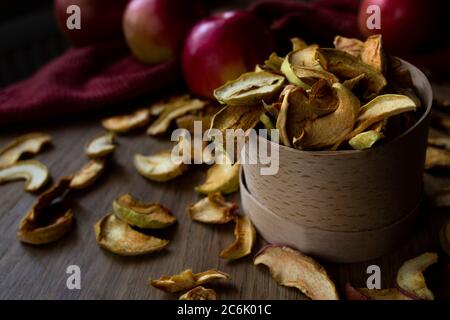 Homemade sun-dried organic apple slices, crispy apple chips, and fresh ripe red apples on an old rustic wooden table Stock Photo