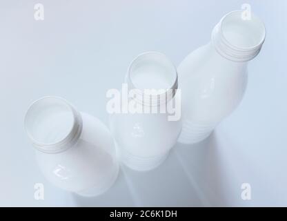 Open empty white plastic milk bottles on White background Stock Photo