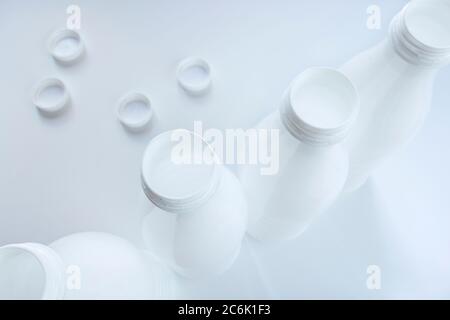 Open empty white plastic milk bottles and caps on White background Stock Photo