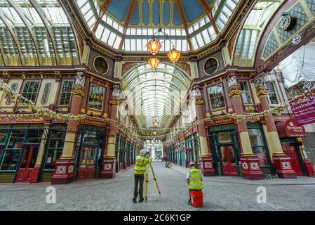 London, UK.  10 July 2020.  Surveyors take advantage of a quiet Leadenhall Market in the City of London to make careful laser measurements.  The historical market would normally be crowded with city workers on a Friday lunchtime but the coronavirus pandemic has left the venue largely unattended as people continue work from home.  The future definition of the workplace may be a hybrid of office work and working from home, resulting in a probable reduction in people working in the area.  Credit: Stephen Chung / Alamy Live News Stock Photo