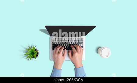 A man typing on a laptop with a cup of coffee with a top view on a birch background. Stock Photo