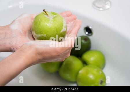 Washing fruit. Hands and soapy green apple Stock Photo