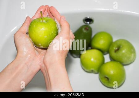 Washing fruit. Hands and soapy green apple Stock Photo