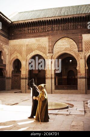 two men walking in the medersa, Medersa Bou Inania, Fez, Morocco Stock Photo