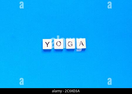 The word YOGA written in wooden letterpress type on a blue background. top view. flat layout. Stock Photo