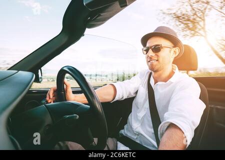 Smiling Man driving cabriolet car by province mountain road inside car view Stock Photo