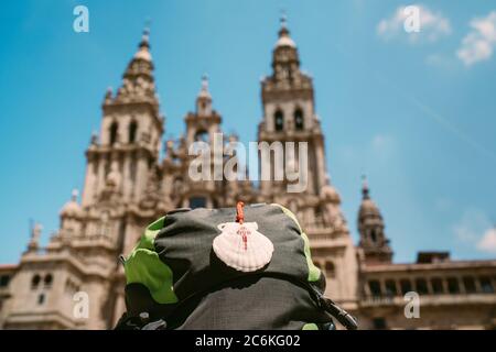 Pilgrim's backpack with famous pilgrims' mascot and sign seashell with Cross of Saint James at  on the Obradeiro square (plaza) - the main square in S