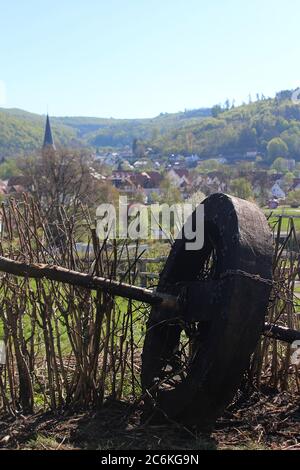 Wooden wheel used for Easter tradition with village of Luegde in the background. Stock Photo
