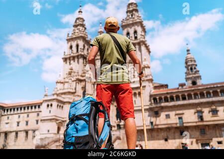 Young backpacker man pilgrim standing on the Obradeiro square (plaza) - the main square in Santiago de Compostela as an end of his Camino de Santiago Stock Photo