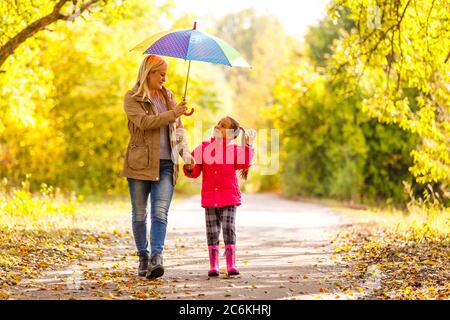 Young mother and her little daughter outdoors in colorful raincoats Stock Photo