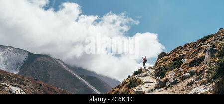Hiker man silhouette on clouds background standing on path going over the Imja Khola valley during an Everest Base Camp trekking route near Tengboche. Stock Photo