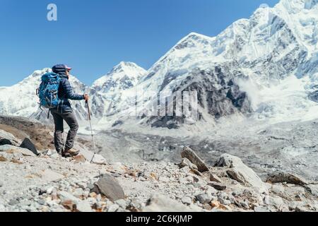 Young hiker backpacker female taking brake in hike walking enjoying Khumbu Glacier. High altitude Everest Base Camp route near Gorakshep,Nepal. Nuptse Stock Photo