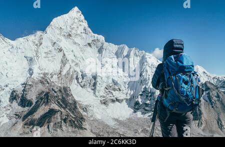 Young hiker backpacker female taking brake in hike walking enjoying Khumbu Glacier. High altitude Everest Base Camp route near Gorakshep,Nepal. Nuptse Stock Photo