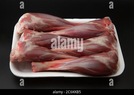 Raw lamb shanks in a white styrofoam container isolated on black background with copy space for text Stock Photo