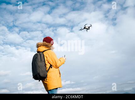 Teenager boy dressed yellow jacket piloting a modern digital drone using remote controller Stock Photo