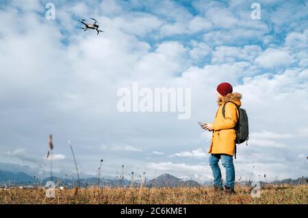 Teenager boy dressed yellow jacket piloting a modern digital drone using remote controller Stock Photo