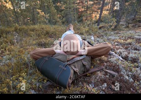Restful young man laying down on the ground of a forest or a park Stock Photo