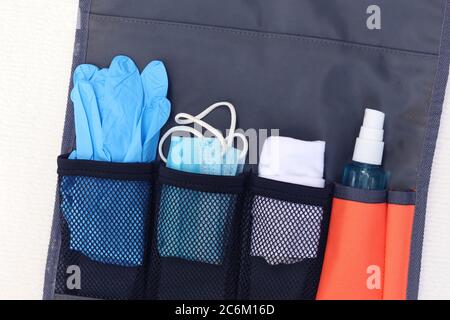 Travel concept in New Normal after Covid-19 pandemic.Hanging bag consisting of medical mask,hand towel,disposable glove and hand sanitizer spray. Stock Photo