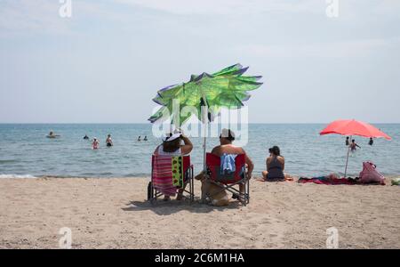 Toronto, Canada. 10th July, 2020. People enjoy leisure time on a beach of Lake Ontario during a heat wave in Toronto, Canada, on July 10, 2020. The temperature in Toronto marked the ninth consecutive day of temperature over 30 degrees Celsius on Friday. Credit: Zou Zheng/Xinhua/Alamy Live News Stock Photo