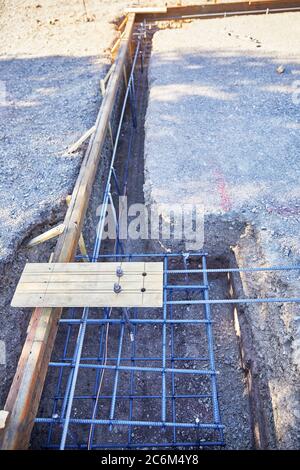 Level building site pad with three foot deep footing trench and concrete forms in place with copper ground wire for electric Stock Photo