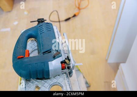 Woodworking works sawing electric jigsaw lies on a plywood sheet Stock Photo