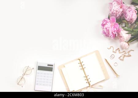 Female diary, golden pen and jewelry, pink peonies, calculator on a white background. Copy space Stock Photo