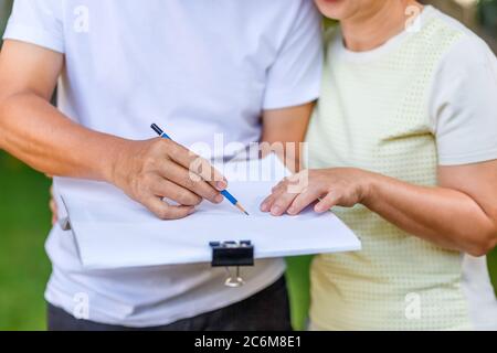 Asian middle-aged couple talking and designing garden plan together in backyard. Stock Photo