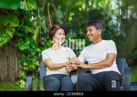 Middle aged couple relax sitting on bench in backyard. Stock Photo
