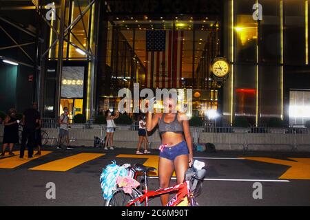 New York, New York, USA. 9th July, 2020. In less than a day, 5th Ave has become a magnet for New Yorkers and especially the African-American community who come to discover and take photos in front of a gigantic Black Lives Matter mural that now lines in front of Trump Tower. 'NYC Mayor is denigrating this luxury Avenue, ' wrote President Trump in a tweet. This young woman dances a gloved hand next to her bike in front of the painted sign at the front door of Trump Tower. Credit: Marie Le Ble/ZUMA Wire/Alamy Live News Stock Photo