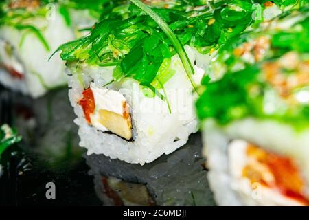 Rolls with fish, cheese and green algae. A traditional Japanese dish. Close up Stock Photo